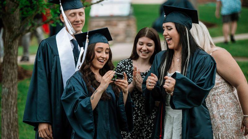 Graduates and students gather to look at camera photo